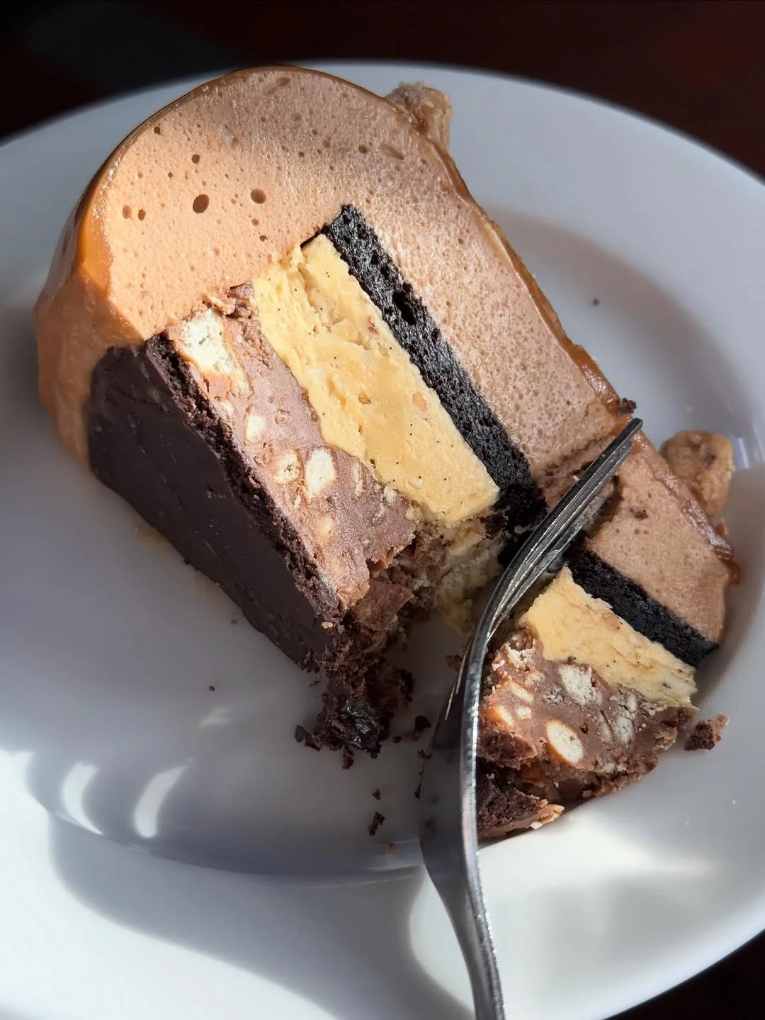The Slice — caramel praline sponge entremet cross-section with dark ganache and vanilla cream layers